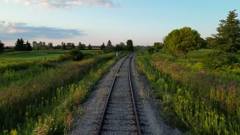 Drone-flight-along-railroad-track-through-scenic-lush-green-countryside