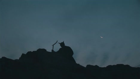 Silhouette-of-man-with-mask-on-climbing-on-top-of-a-cliff-on-the-dusk-without-sunlight