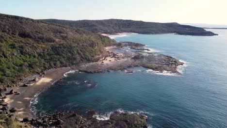 Drone-aerial-landscape-scenery-pan-shot-over-rocky-headland-reef-Frazer-Beach-Lake-Munmorah-National-Park-Ocean-tourism-travel-Central-Coast-NSW-Australia-4K