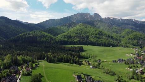 Landscape-fly-by-of-the-legendary-Giewont-peak-in-the-Polish-Tatry-Mountains,-farmland,-forests-near-Zakopane,-Poland,-a-resort-town-with-traditional-Goral-architecture-2