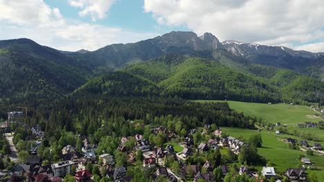 Landscape-fly-by-of-the-legendary-Giewont-peak-in-the-Polish-Tatry-Mountains,-farmland,-forests-near-Zakopane,-Poland,-a-resort-town-with-traditional-Goral-architecture-5