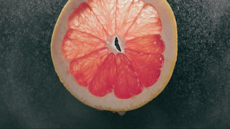 Fresh-Grapefruit-Slice-Splashed-by-Strong-Water-Droplet-Mist-in-Slow-Motion-with-Backlit-Black-Background