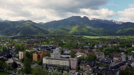 Flyover-of-Zakopane,-Poland,-a-resort-town-village-with-traditional-Goral-architecture-near-the-Polish-Tatra-mountains,-farmland,-forests,-Giewont-peak,-and-Great-Krokiew-Ski-Jump---4K-Tracking-Back-2