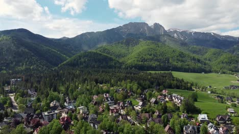 Landscape-fly-by-of-the-legendary-Giewont-peak-in-the-Polish-Tatry-Mountains,-farmland,-forests-near-Zakopane,-Poland,-a-resort-town-with-traditional-Goral-architecture-1