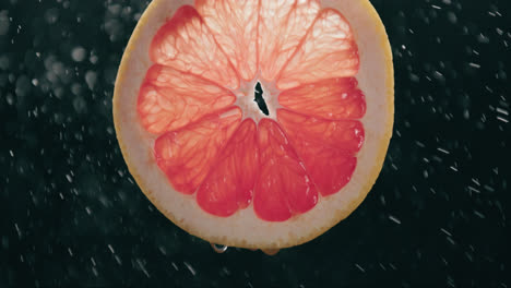 Fresh-Grapefruit-Slice-Splashed-by-Water-Droplet-Mist-with-Liquid-Drip-in-Slow-Motion-Backlit-Black-Background