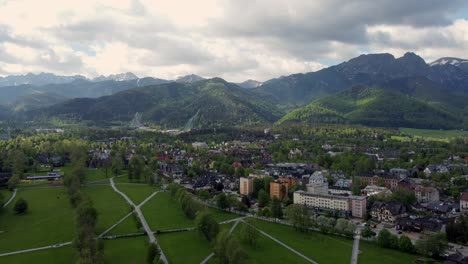 Flyover-of-Zakopane,-Poland,-a-resort-town-village-with-traditional-Goral-architecture-near-the-Polish-Tatra-mountains,-farmland,-forests,-Giewont-peak,-and-Great-Krokiew-Ski-Jump---4K-Tracking-Up