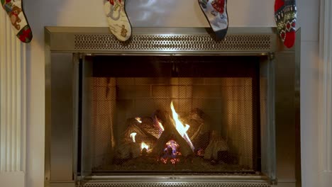 Static-shot-of-wood-burning-in-stylish-fireplace-with-christmas-socks-hanging,-Season-concept