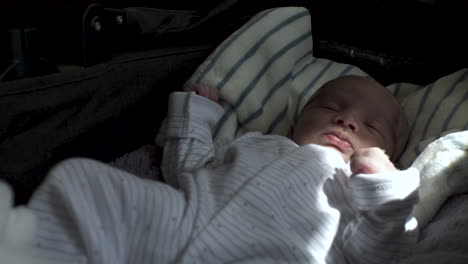 Schlafender-Neugeborener-Junge-Im-Baby-Wächst-Langsam-Und-öffnet-Die-Augen-Mit-Sonnenlicht-Auf-Dem-Linken-Arm