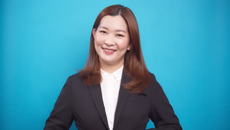 Porträt-Der-Asiatischen-Glücklichen-Lächelnden-Geschäftsfrau,-Die-Arrangierten-Schwarzen-Anzug-Tut,-Der-Auf-Blauem-Hintergrund-Lokalisiert-Wird