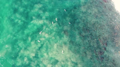 Drone-aerial-video-pan-shot-of-Pacific-Ocean-waves-on-reef-surfers-surfing-crystal-clear-water-travel-tourism-Old-Bar-Taree-NSW-coastline-Australia-4K