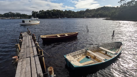 Rowing-boats-floating-next-to-a-wooden-pier-in-Strahan,-West-Coast-of-Tasmania