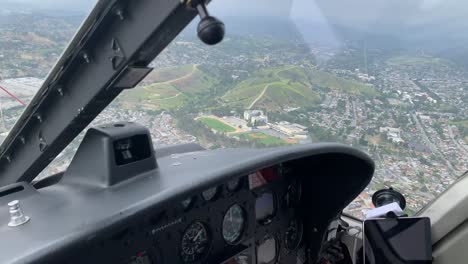 Cockpit-of-helicopter-flying-over-city