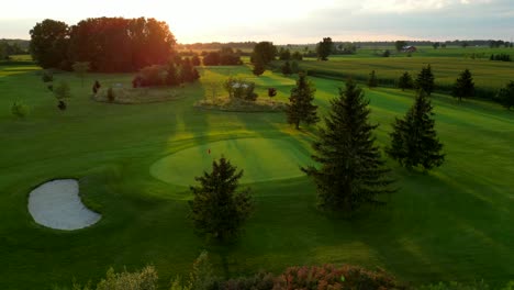 Beautiful-aerial-view-golf-course-green-and-hole-at-sunset-in-nature