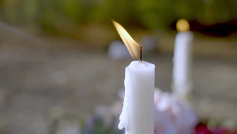 White-candle-burning-on-top-of-new-grave,-close-up-slow-motion-view