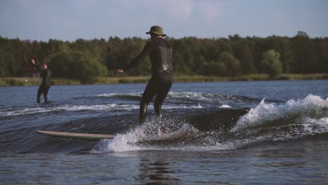 Surfer,-Der-Longboard-In-Welle-Surft,-Berührt-Welle-Mit-Querschritt-Und-Nasenfahrt-Hinter-Einem-Boot-In-Zeitlupe