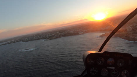 POV-Flying-in-a-helicopter-over-the-coast-during-sunset-in-Sydney,-Australia