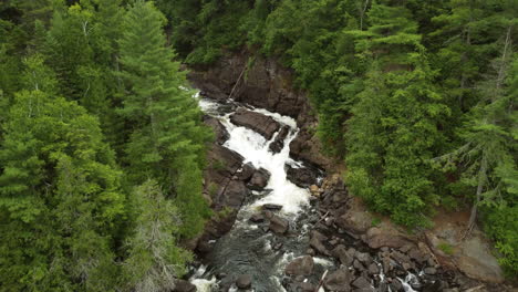 Aerial-view-of-water-flowing-through-a-forest-at-Oxtongue-Falls,-Algonquin-Park,-Ontario,-Canada