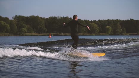 Surfer,-Der-Longboard-In-Welle-Mit-Querschritt-Und-Nasenfahrt-Hinter-Einem-Boot-In-Zeitlupe-Surft-1