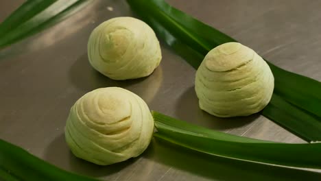 Green-Chinese-Pastry-on-Table-Decorated-with-Pandan-Leave,-Close-Up