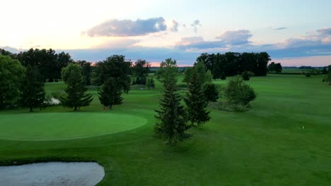 Peaceful-sunset-drone-flight-on-golf-course-to-putting-green-with-red-flag