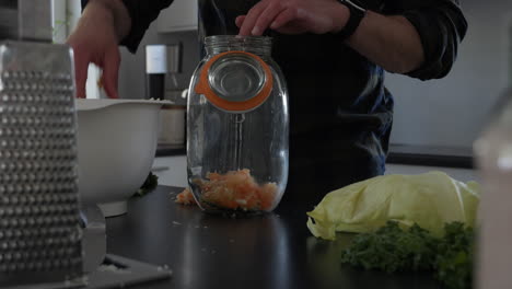 Filling-up-Glass-Jar-with-Carrot,-DIY-Vegetable-Fermentation-Project-at-Home,-Dolly