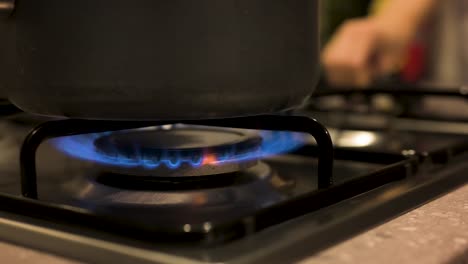 Turning-gas-stove-on-with-pot-on-top-close-up,-slow-motion