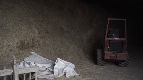 Medium-shot-of-farm-equipment-and-hay-inside-a-barn