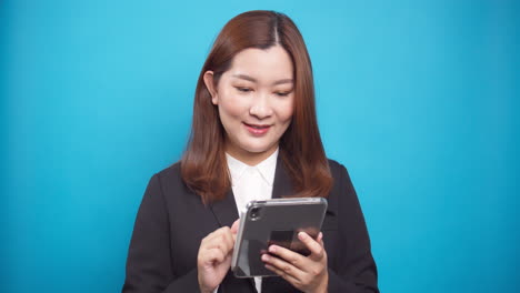 Schöne-Asiatische-Geschäftsfrau-In-Einem-Schwarzen-Anzug,-Der-Ein-Digitales-Tablet-Für-Die-Planung-Von-Online-arbeiten-Mit-Drahtloser-Technologie-Auf-Blauem-Hintergrund-Verwendet-1