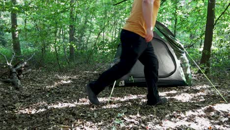 Tourist-man-adjusting-the-tent-sides-at-a-campsite-in-the-woods