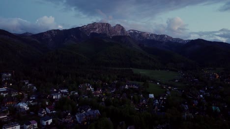 Night-time-flyover-of-Zakopane,-Poland,-a-resort-town-against-the-Tatra-Mountains,-and-its-stunning-Goral-traditional-architecture