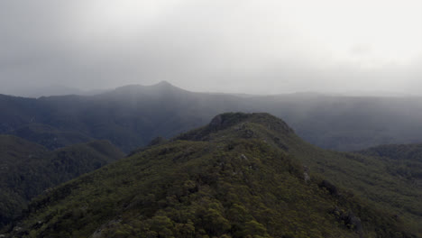 Aerial:-Drone-flying-over-a-rocky-forested-ridge-line-near-Cradle-Mountain,-Tasmania