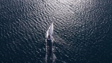 Sailing-vessel-exploring-deep-blue-ocean-with-bright-sunshine-reflecting-on-surface