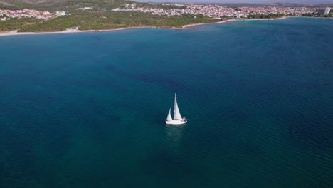 Sailing-boat-cruising-in-calm-blue-water-along-Croatia-shore,-aerial