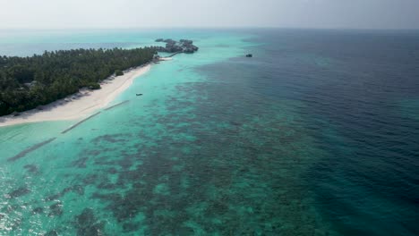 Arrecife-Tropical-Que-Rodea-Los-Resorts-De-La-Isla-De-Maldivas-Con-Bungalows-Sobre-El-Agua-En-La-Distancia