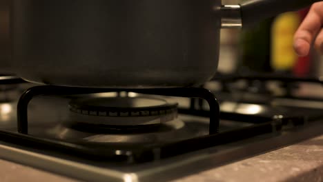 Turning-gas-stove-off-and-removing-pot-close-up,-slow-motion