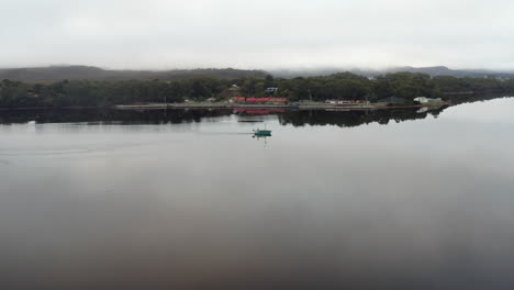 Aerial:-Drone-flying-around-a-fishing-boat-on-a-large-lake-in-Strahan-Tasmania,-Australia