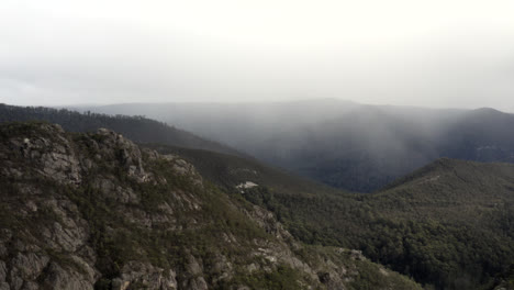 Aerial:-Drone-flying-over-rough-rocky-terrain-towards-a-wet-weather-front-in-Tasmania,-Australia