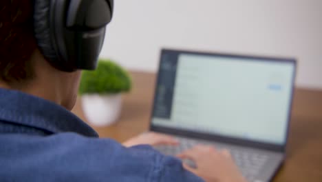 Guy-putting-on-his-headphones-and-scrolling-on-his-laptop
