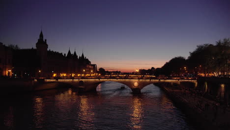 Panorama-De-Conciergerie-Y-Puente-Iluminado-Pont-Au-Change-En-La-Noche,-París-Francia-4k-Verano