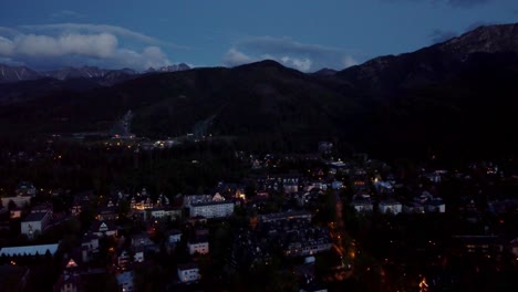 Stunning-night-time-flyover-of-Zakopane,-Poland,-a-resort-town-against-the-Tatra-Mountains,-and-its-stunning-Goral-traditional-architecture