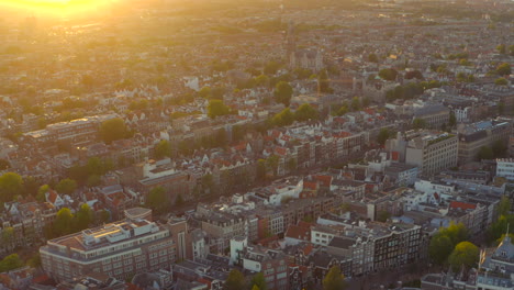 Dolly-Back-Drohne-Schoss-über-Berühmte-Häuser-Im-Zentrum-Von-Amsterdam,-Die-Bei-Sonnenuntergang-Von-Hinten-Beleuchtet-Wurden