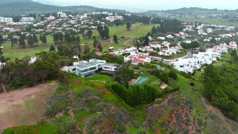 Aerial-orbiting-over-mansion-at-green-hillside,-exclusive-condominium-in-Maitencillo,-Chile