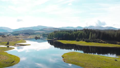 Breathtaking-Scotland-lake-landscape-with-forests-on-sunny-day,-drone