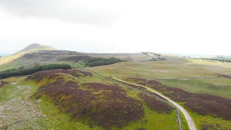 Path-winding-through-Lomond-Hills-rugged-highland-in-Scotland,-drone