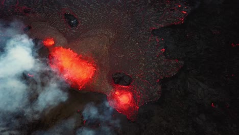 Aerial-top-view-of-magma-and-lava-erupting-in-Meradalir-valley,-from-Fagradalsfjall-volcano,-with-smoke-coming-out