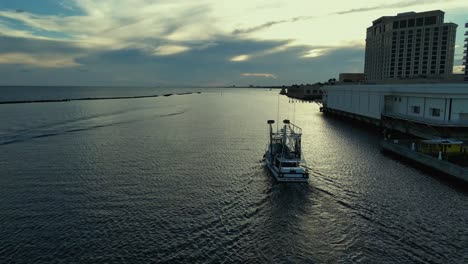 Aerial-view-of-commercial-fishing-boat-heading-out-to-work-in-Biloxi,-Mississippi-at-sunset