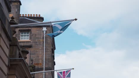 Scottish-flag-on-flagpole-blown-by-wind-on-Royal-Mile-house,-Edinburgh
