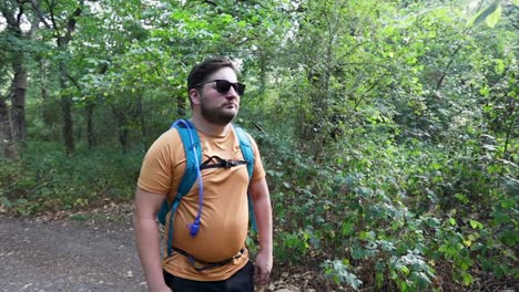 Young-man-with-a-backpack-and-sunglasses-comes-out-of-the-woods-and-realizes-he-is-lost-then-walk-away