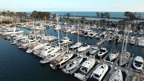 Luxury-sailboats-moored-at-Dana-Point-Marina-with-Pacific-Ocean-in-Backgound,-Aerial-ascending-view