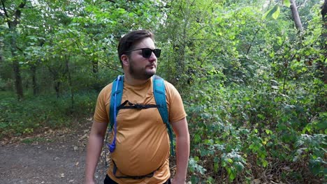 Young-man-with-a-backpack-and-sunglasses-realizes-he-is-lost-in-the-woods-and-walks-the-other-way